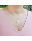 Pear-shaped Australian opal pendant with fiery red-orange hues in 14k yellow gold, worn on a woman.
