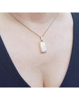 Necklace with a natural opal pendant worn by a person against a white background