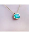 18K yellow gold necklace with a vibrant deep green emerald solitaire in an east-west setting.