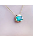 18K yellow gold necklace with a vibrant deep green emerald solitaire in an east-west setting.