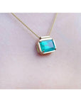18K yellow gold necklace with a vibrant deep green emerald solitaire in an east-west setting.