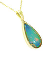 Opal pendant necklace on a gold chain against a white background