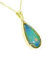 Opal pendant necklace on a gold chain against a white background