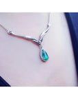1.28 carat pear cut emerald necklace in 14K white gold with diamond accents and chevron design.