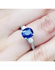 Women's 14K white gold ring with a deep blue oval sapphire and two round side diamonds.