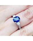 Women's 14K white gold ring with a deep blue oval sapphire and two round side diamonds.