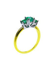 Lucida style three-stone emerald ring with round cut green emeralds prong-set in white and yellow gold.
