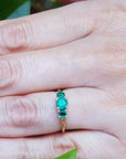 A three stone emerald ring round cut on a person's hand.