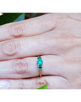 Round cut three-stone emerald ring with prong-set stones in Lucida style, crafted in white and yellow gold.