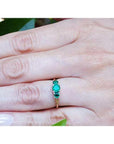 Round cut three-stone emerald ring with prong-set stones in Lucida style, crafted in white and yellow gold.