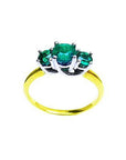Round cut three-stone emerald ring with prong-set stones in white and yellow gold.