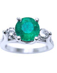 Top view of a round cut colombian emerald ring with side natural diamonds in white gold