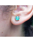 An ear wearing a Colombian emerald stud earring made of 14k white gold and push backs.