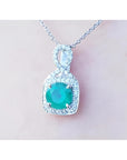 1.08 ct. round emerald and diamond pendant in 18K white gold, featuring a deep bluish-green emerald.