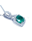 Round emerald and diamond halo pendant in 18K white gold with a deep bluish-green gemstone.