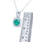 Emerald pendant on a chain with a ruler for scale on a white background