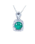 Round deep bluish-green emerald and diamond halo pendant in 18K white gold.