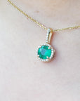 A closer view of a natural round cut emerald pendant necklace on a person's neck.