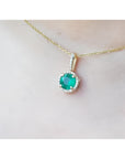 Round cut Colombian emerald pendant with halo diamonds on a 14K gold chain.