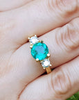 A 18k yellow gold with round cut emerald rings on a hand.