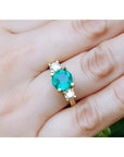 GIA certified F1 Colombian emerald three-stone ring with round diamonds in 18K yellow gold.