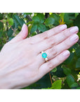 Hand wearing a 2.44 ct. GIA F1 Colombian emerald three-stone ring with diamonds in 18K yellow gold.