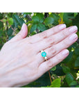 Hand wearing a 2.44 ct. GIA F1 Colombian emerald three-stone ring with diamonds in 18K yellow gold.