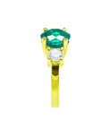 This round cut natural emerald ring with side diamonds made in 18k yellow gold is displaying its top and side profile.