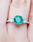 Emerald and baguette side diamonds ring for ladies on a finger.