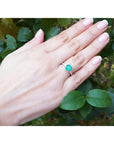 Round cut Colombian emerald ring with baguette side diamonds on a woman's hand, 14K white gold.