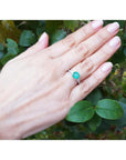 Round cut Colombian emerald ring with baguette side diamonds on a woman's hand, 14K white gold.