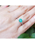 Round cut Colombian emerald ring with baguette side diamonds in 14K white gold on a hand.
