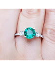 Emerald and baguette side diamonds ring for ladies in 14k white gold on a finger.