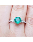 Emerald and baguette side diamonds ring for ladies in 14k white gold on a finger.