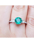 Emerald and baguette side diamonds ring for ladies in 14k white gold on a finger.