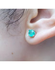 Round-cut Colombian emerald stud earring in 14k white gold, worn on an ear.