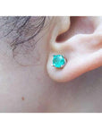 Round-cut Colombian emerald stud earring in 14k white gold, worn on an ear.