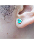 Round-cut Colombian emerald stud earring in 14k white gold, worn on an ear.