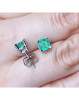 Round 0.89 ct. green emerald stud earrings in 14k white gold, displayed on a hand.