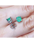 Round 0.89 ct. green emerald stud earrings in 14k white gold, displayed on a hand.
