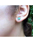 Round 0.89 ct. Colombian emerald stud earring in 14k white gold worn on an ear.