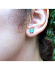 Round 0.89 ct. Colombian emerald stud earring in 14k white gold worn on an ear.
