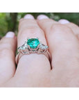 1.00 ct. round emerald ring with trillion side diamonds on a hand, 14K white gold.