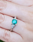 Round cut and trillion side diamond ring for women on a hand with a blurred background.