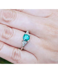 Round cut and trillion side diamond ring for women on a hand with a blurred background.