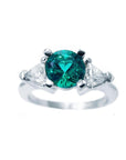 This round cut emerald ring with trillion side diamonds white gold has a top profile sides view.