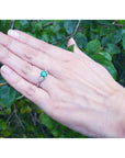 1.00 ct. round emerald ring with trillion side diamonds on a hand, 14K white gold.