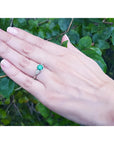 1.00 ct. round emerald ring with trillion side diamonds on a hand, 14K white gold.