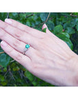 1.00 ct. round emerald ring with trillion side diamonds on a hand, 14K white gold.
