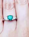 A lady's emerald ring round cut on a person's finger.